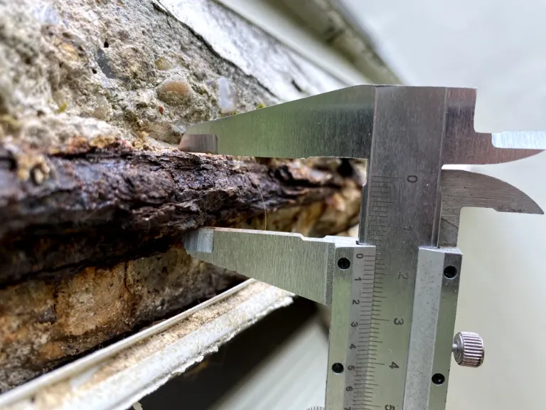Relevé technique du diamètre résiduel d'un fer à béton corrodé à l'aide d'un pied à coulisse, pour évaluation de la perte de section.