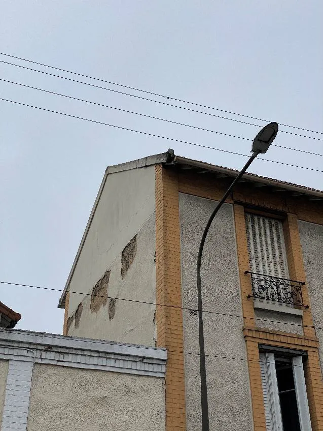 Façade présentant un décollement de l'enduit avec dégradations visibles du revêtement extérieur à Argenteuil.