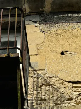 Fissure transversale importante visible au droit d'un linteau avec ouverture apparente affectant la maçonnerie.