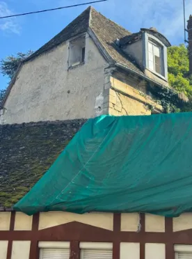Fissure verticale marquée visible sur le pignon d'un bâtiment, affectant la façade sur une hauteur importante.