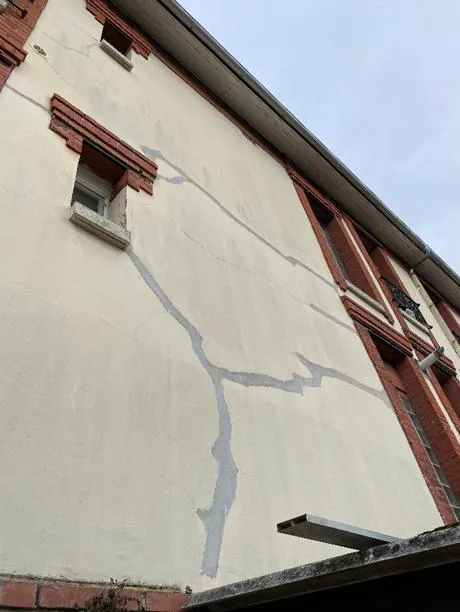 Fissures visibles sur une paroi ayant fait l'objet d'un colmatage, avec traces de réparation du revêtement.