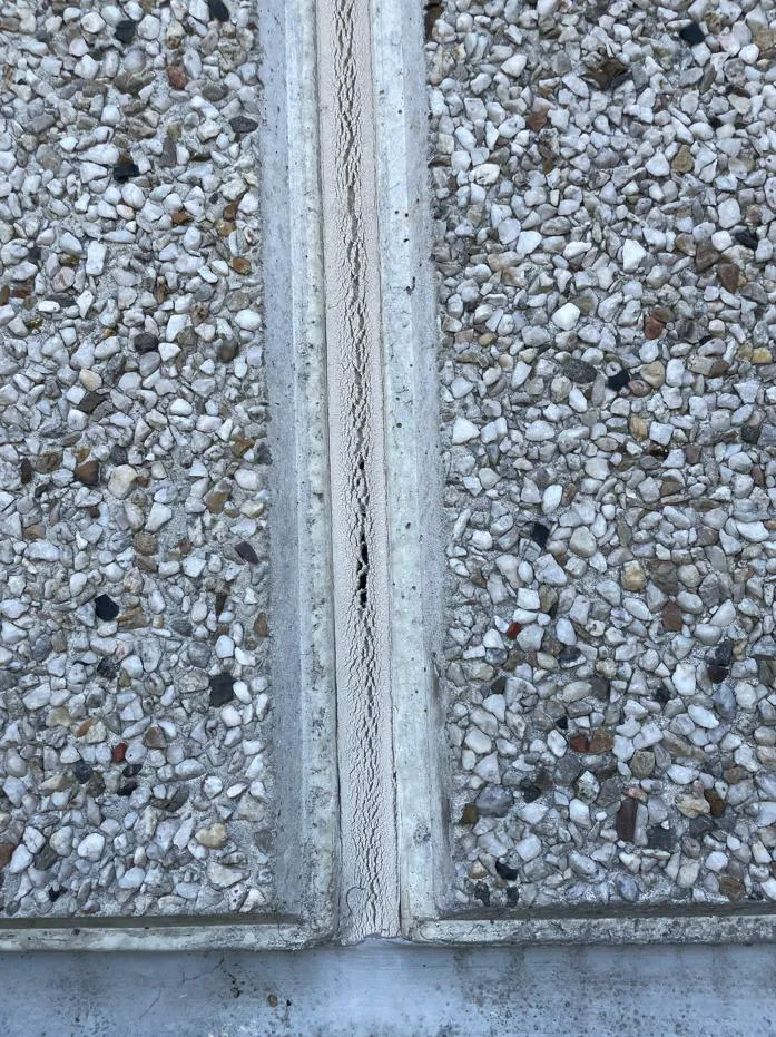 Vue rapprochée d'un joint de dilatation non étanche laissant apparaître des signes d'usure et d'altération.