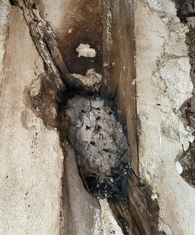 Vue détaillée d'un poteau et d'un contreventement présentant des traces de calcination après un incendie.
