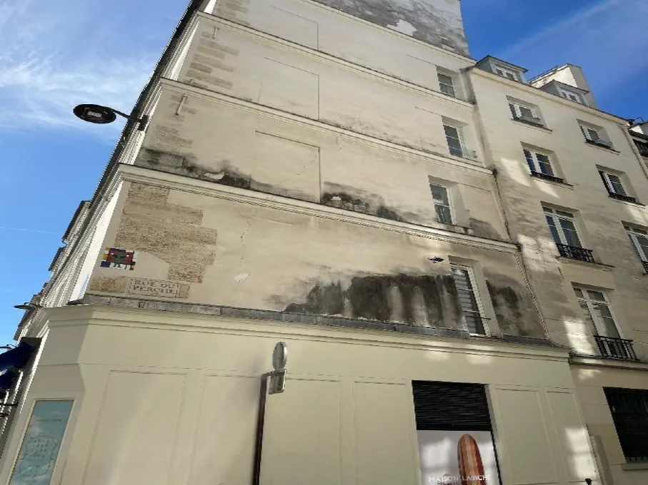 Façade présentant des traces d'humidité ainsi que des indices d'anciennes infiltrations visibles sur le revêtement.